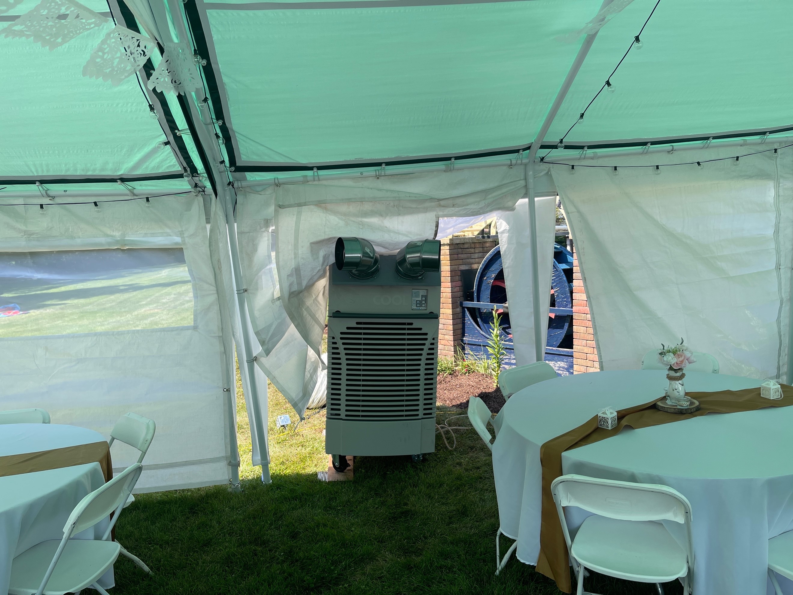 Outdoor enclosed tent with a 5-ton rental air conditioner installed for outdoor summer party. 